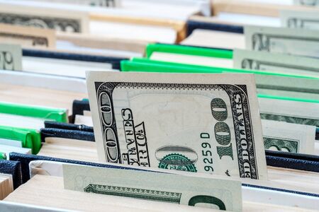 banknote hundred dollars sticking out from the book which is in book number of other books, too,...