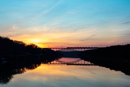 sky during sunset and railway bridge installed across the river in the river reflects the sky and the bridge. on the bridge railway structure passed to his halfの写真素材