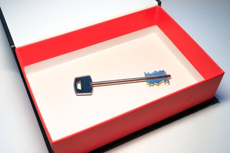 a large metal key for the door lock in a rectangular cardboard box with red edges