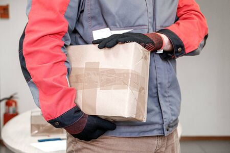 a man in gloves holds a parcel sealed for delivery. delivery of parcels by employeeの写真素材