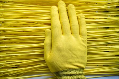 on top of the yellow background of plastic threads is a hand in a yellow glove. the superiority of the yellowの写真素材