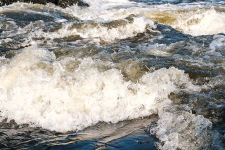 rapid flow of the mountain river yellow water with foam and bubbling close up