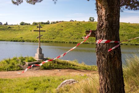 the cross by the river is fenced with a red ribbon. crime scene