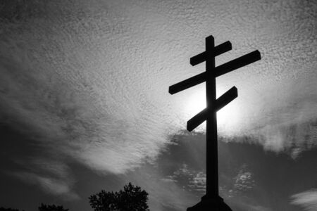black and white photo of an Orthodox cross against the skyの写真素材