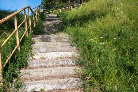 a dilapidated old concrete staircase leading up on both sides of the grass grows. abandoned staircase leading to the unknownの写真素材