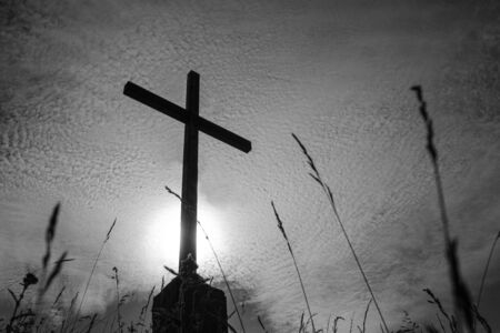 black and white photo of a cross against the sky in small clouds. tragic atmosphereの写真素材