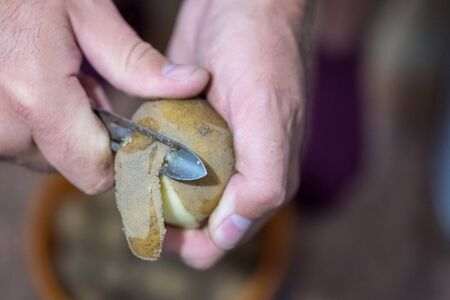 a man cleans a special knife potatoes from the skinの写真素材
