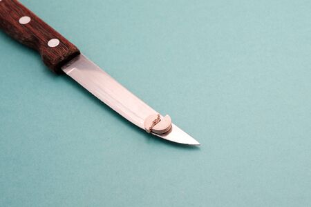 on a blue background a knife on the blade of which a medicine tablet divided in half broken. drug dose sharingの写真素材