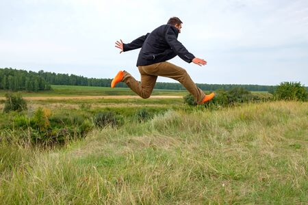 a man running across the field in orange socks jumped high with joy. striding across the fieldの写真素材
