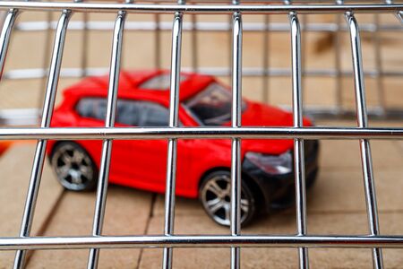 A red toy car is closed like a metal cage. jail for a car arrested for finesの写真素材