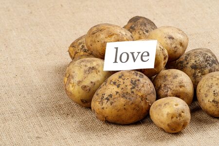 unwashed potatoes on a rough old cloth on it is a leaflet with the inscription love. when potatoes are your favorite dishの写真素材