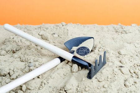 shovel and rake on each other in the sand. abandoned tools in the sand and moneyの写真素材