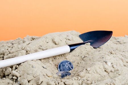 a shovel lies on the sand and the ruble is nearby. digging tool and moneyの写真素材