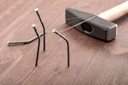 nails tied with a large heavy hammer on a wooden table. social injustice people and government...