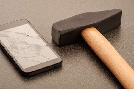 hammer breaking a smartphone screen on a ceramic surface. broken screenの写真素材