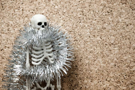 the human skeleton is wrapped with shiny New Year's decoration on the left of it is the free surface of a beige flower. holiday and events there will be no epidemicの写真素材