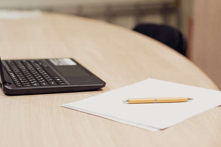 laptop and fountain pen on a wooden table, background out of focus. no people in the frame