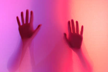 silhouette of the girl's palms photograph through a fabric with lighting of different colors....
