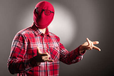 a man in a red shirt on a black background on his head, a hat is not visible. hands folded in...