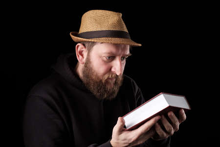 a white bearded man in a hat tenderly holds a thick book in his hands. respect for booksの写真素材