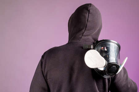 the man in the hood turned his back, a gas mask on his shoulder. leaving with respiratory protectionの写真素材
