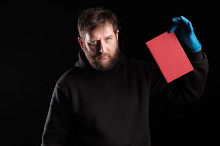 a bearded man holds a book in his gloved hand. books that are prohibited
