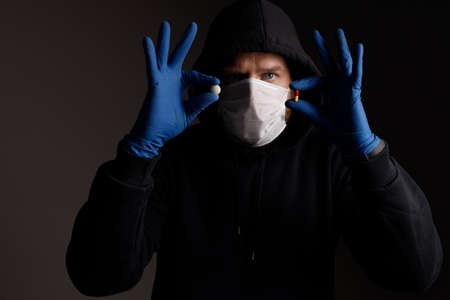 a white man with a beard, wearing a medical mask and rubber gloves, demonstrates two pills for the disease. a medicine to choose from in each handの写真素材