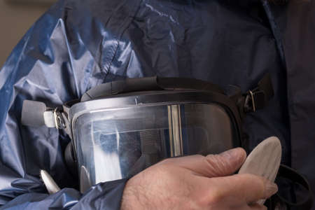 an employee of the pest control department holds a protective mask in his hand. special clothing for a chemical processing employeeの写真素材