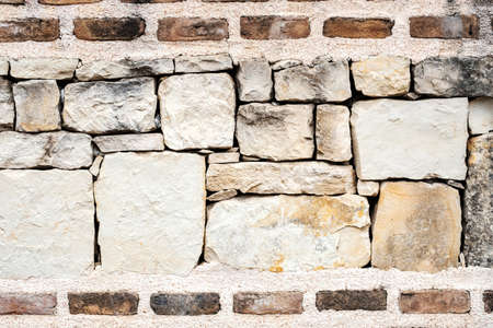 stone wall of large elements in cretinine and bricks on top and bottom, old building