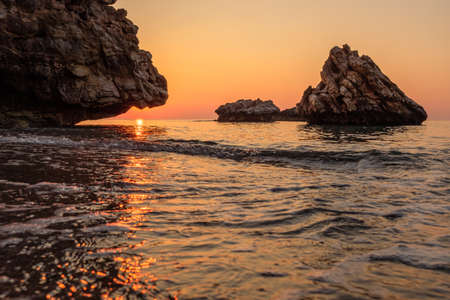 rock in the sea on the coast at dawn on the sea waves on the waterの写真素材