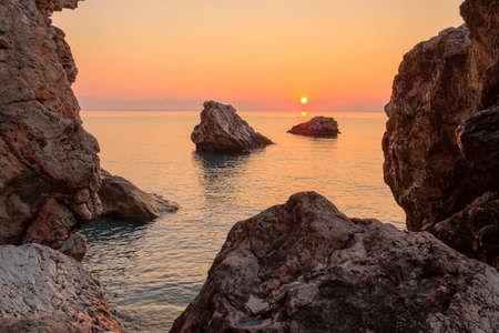 orange dawn in the early morning on the sea rocky shore. wild beach in Beldibi Turkeyの写真素材