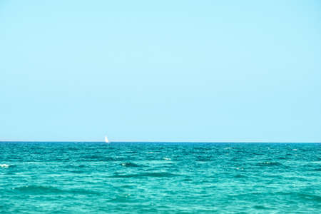 the sea sky is very far away a lonely white ship floats on the horizon lineの写真素材