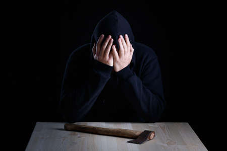 the man at the table in front of him regrets that he committed a crime. man in black on a dark...
