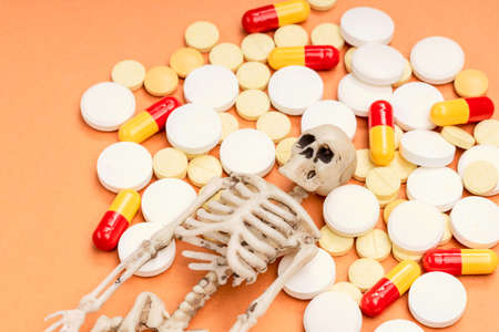 human skeleton and many pills next to it. pill overdoseの写真素材