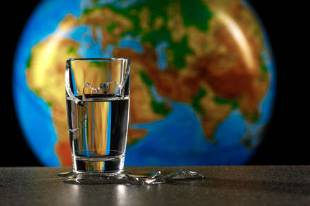 broken glass from which water flows, in the background the planet earth africa and eurasia. concepts...