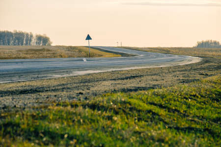 turn on the road, grass grows on the side of the road. evening on a country road
