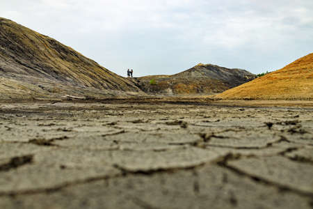 on the shore of a dried-up reservoir in the distance there is a loving couple, love and droughtの写真素材