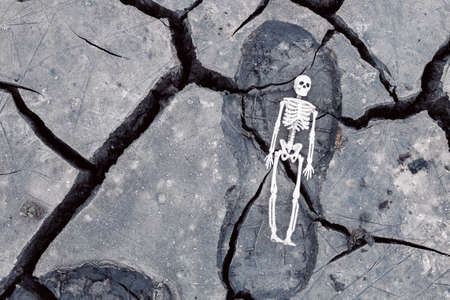 a footprint from a shoe on cracked soil, containing a human skeleton. death is on his heelsの写真素材