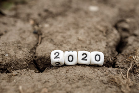2020 numbers on dice are stuck in a crack in the ground. results of a bad yearの写真素材
