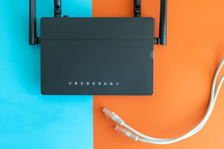 a black router on a bright two-color background, a cable stretches towards it from below