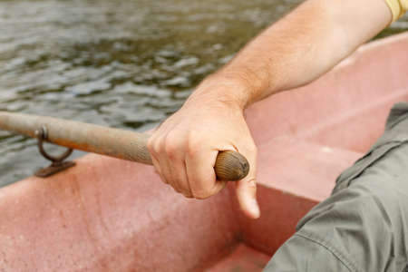 a man's hand holds on to the paddle while sailing on a boat. background nature and river