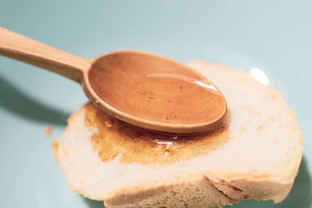 honey in a wooden spoon and a piece of butter bread. breakfast is healthy and sweetの写真素材