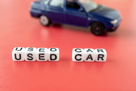 used car written on cubes in the foreground, toy auto backgroundの写真素材