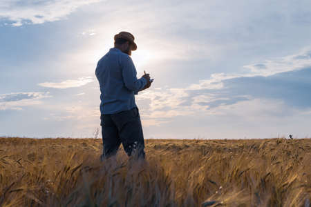 a man farmer in a hat stands on the field and keeps a record of planning work for the day. make plans early in the dayの写真素材