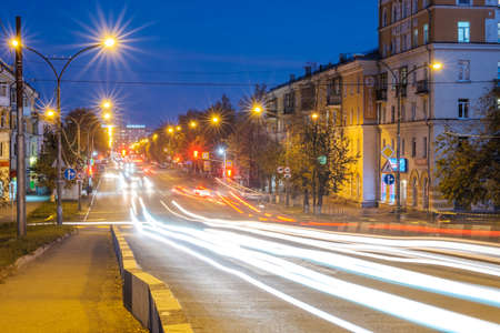 Russia, Kamensk-Uralsky, October 4, 2019 line of lights from cars driving along the street of a small town at night. traces of headlights on the streetの写真素材