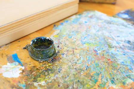 a jar of paint left at the workplace of an artist painting a picture with paints