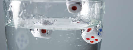 game dice are falling into a glass with water, selective focus. stop motion play in waterの写真素材