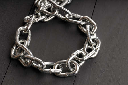 a shiny steel chain on a dark background lies in the form of a loop. steel collarの写真素材
