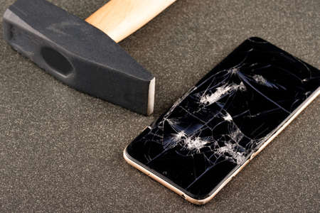 hammer broken smartphone lying nearby. break your phone with angerの写真素材