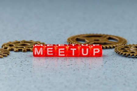 meetup inscription from letters on cubes on a light blue background on the back of metal gearsの写真素材